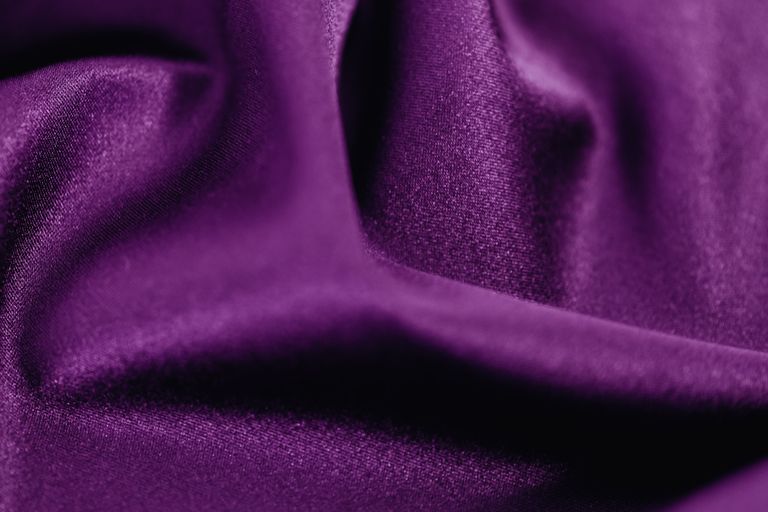 Violetter Stoff mit weichen, eleganten Falten als dekorativer Hintergrund.